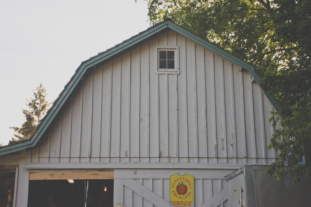 white and gray barn beside green tree