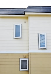 beige and white painted house with three open glass windows