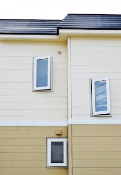 beige and white painted house with three open glass windows