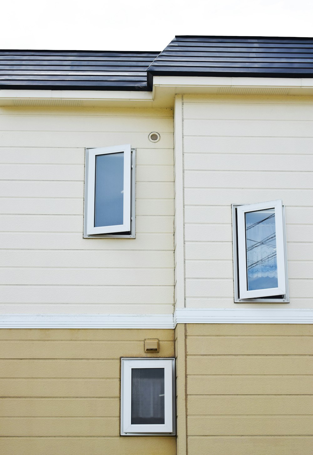 beige and white painted house with three open glass windows