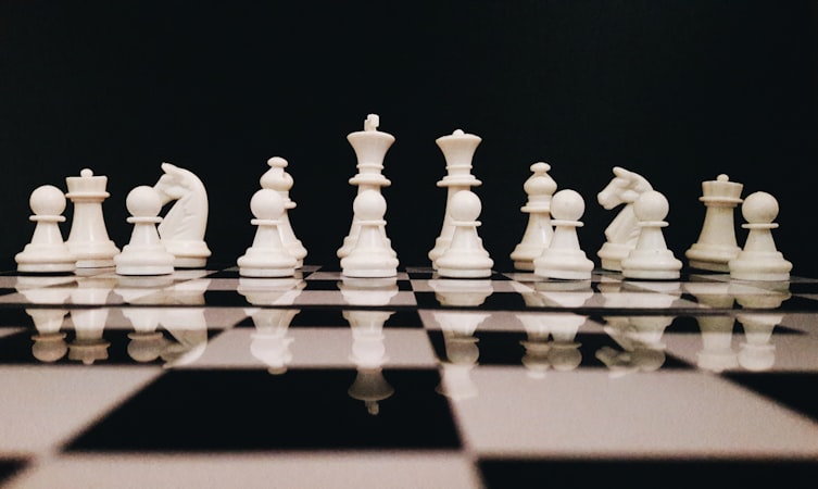 White chess game pieces set arranged on a board showing the opening setup