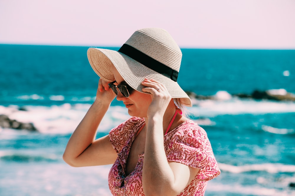 woman holding her hat near seashore