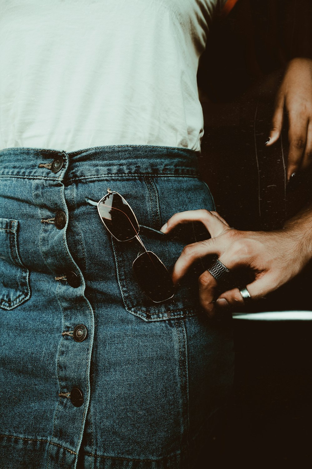 person touching blue denim button-up skirt with sunglasses