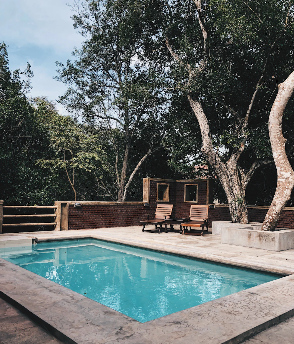 Two lounge chairs on the sun deck beside a clear blue pool