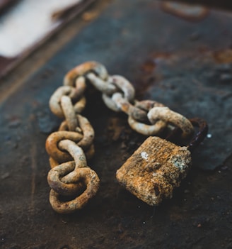 selective focus photography of gray rust-covered chain and padlock