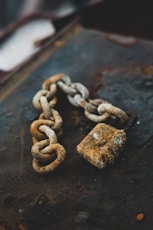 selective focus photography of gray rust-covered chain and padlock