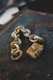 selective focus photography of gray rust-covered chain and padlock