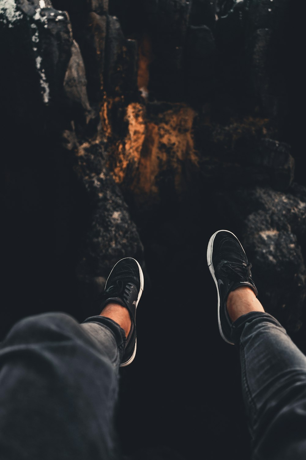 person wearing black denim jeans and low-top sneakers