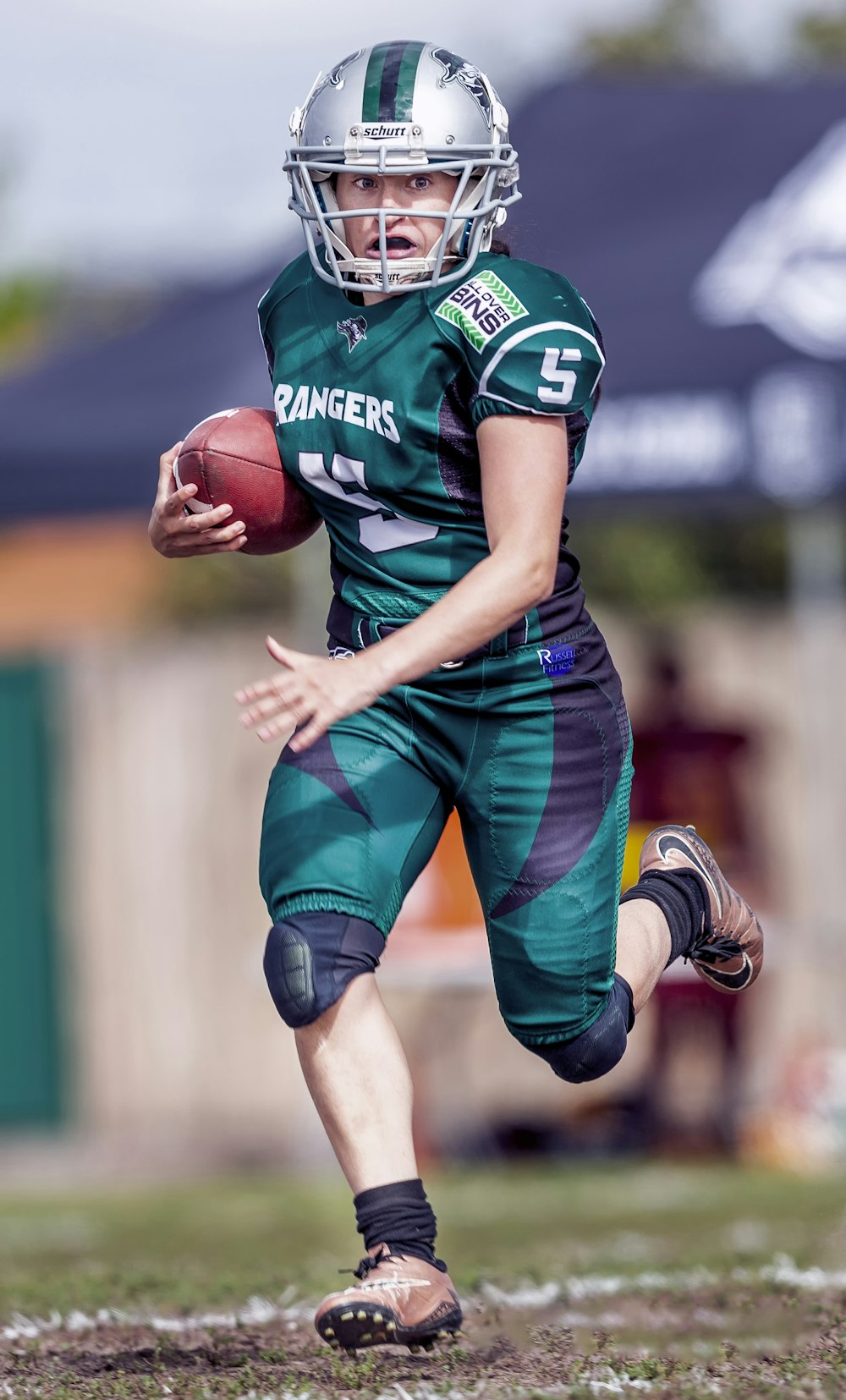 football player holding football while running