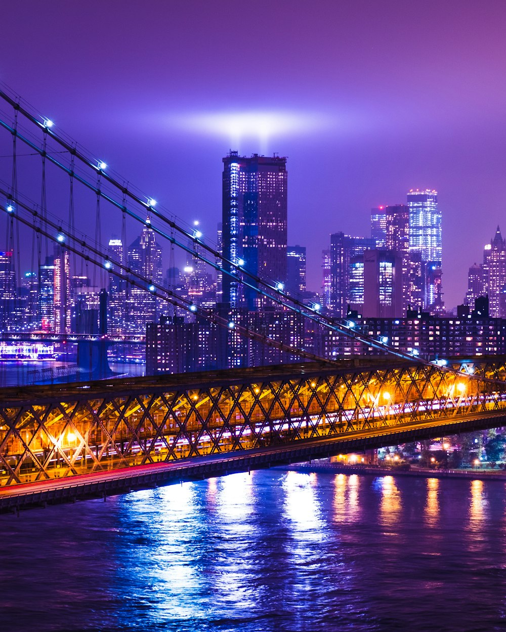 photography of suspension bridge and high-rise building during nighttime