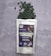 A package of spirulina tablets lies on a grey textured surface. The package is white with a colorful label displaying text and graphics. Green tablets spill out from the top of the package, scattering across the surface.