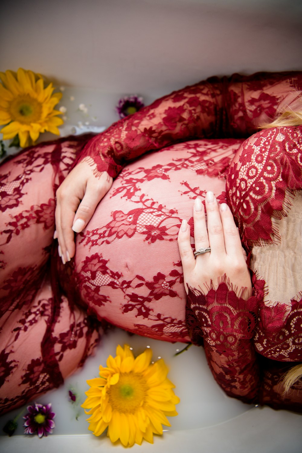 pregnant woman laying on tub with water and flowers