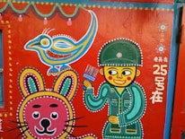 A vibrant mural painted on a wall, featuring a stylized soldier holding a brush, a colorful cartoon bird, and a whimsical rabbit. Intricate dotted patterns in various colors accentuate the figures, and there are decorative floral motifs and Chinese text.
