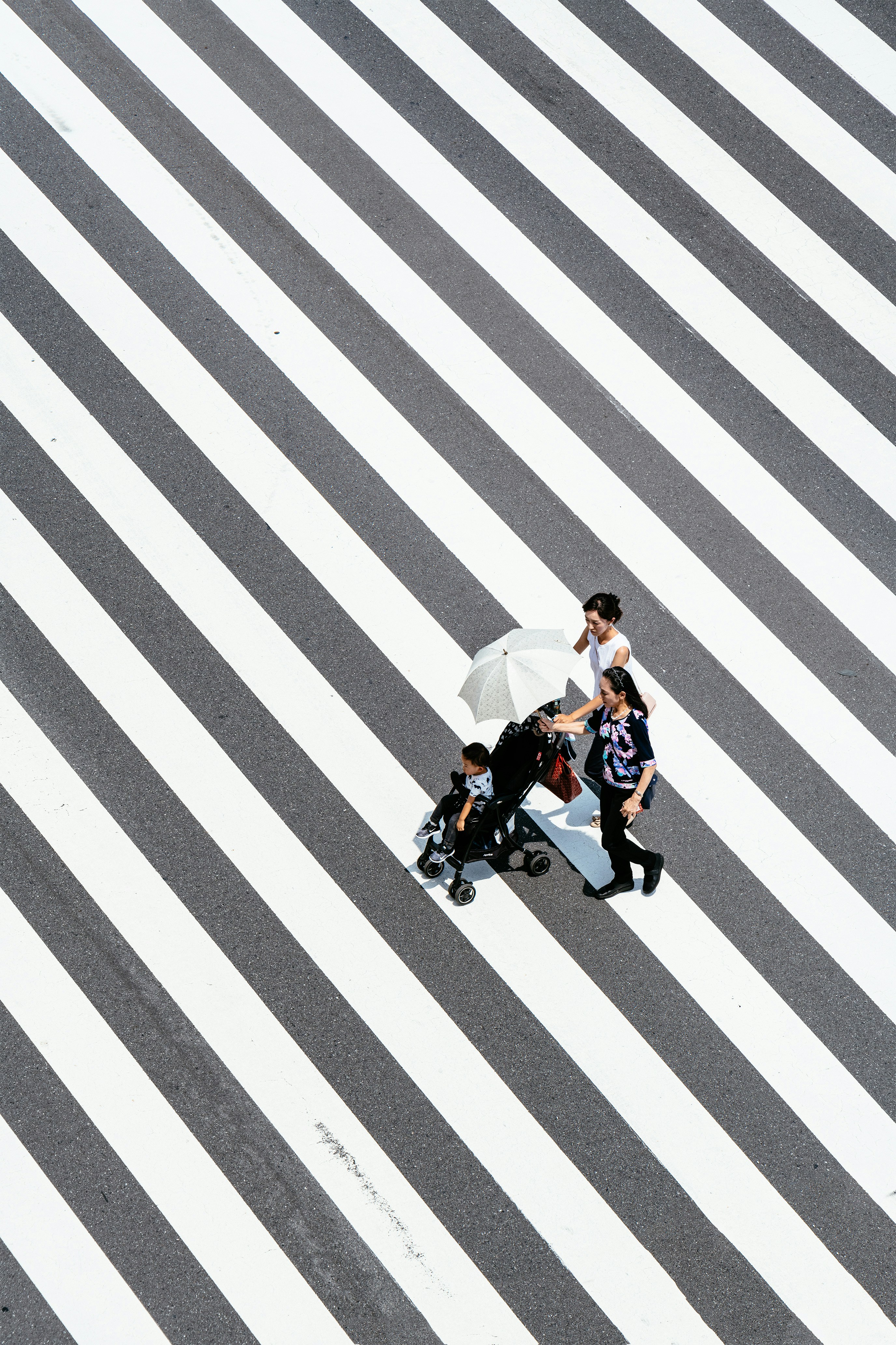 two women and baby crossing striped floor