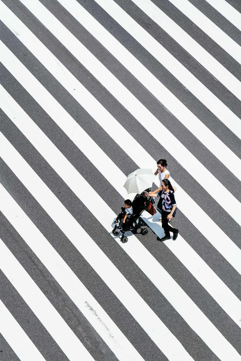 two women and baby crossing striped floor