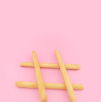 four brown wooden sticks on pink surface