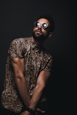 man wearing brown and black leopard print button-up T-shirt and black sunglasses crossing hands down while looking up