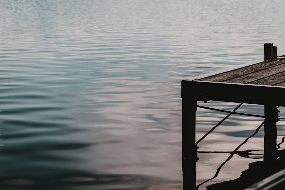 calm body of water near brown wooden ocean dock