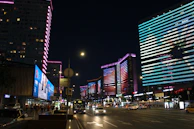A bustling city street at night illuminated by colorful neon lights.