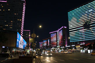 A bustling city street at night illuminated by colorful neon lights.