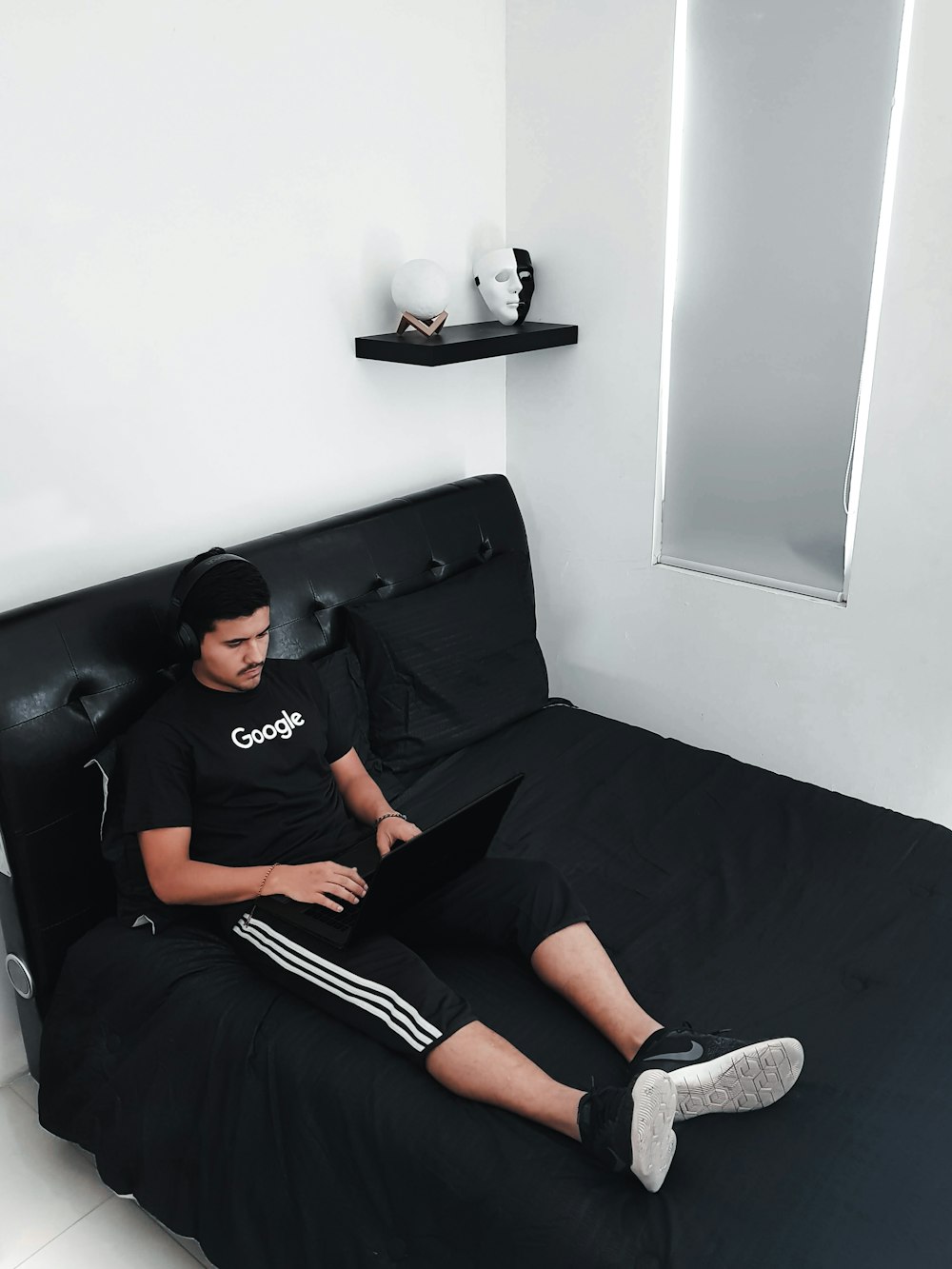 노트북 컴퓨터를 사용하여 침대에 앉아있는 남자