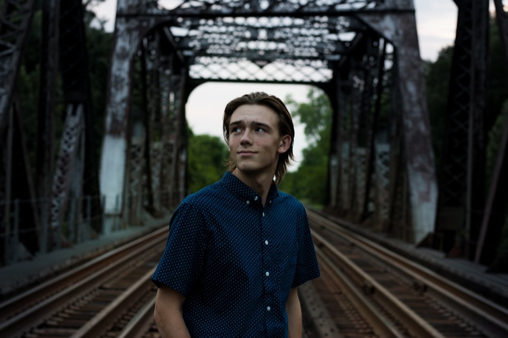 man staining in the middle of a bridge rail