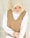 A woman wearing a beige hijab and a brown sleeveless vest over a white shirt. She is looking down with a serene expression, and her hands are gently clasped in front of her.
