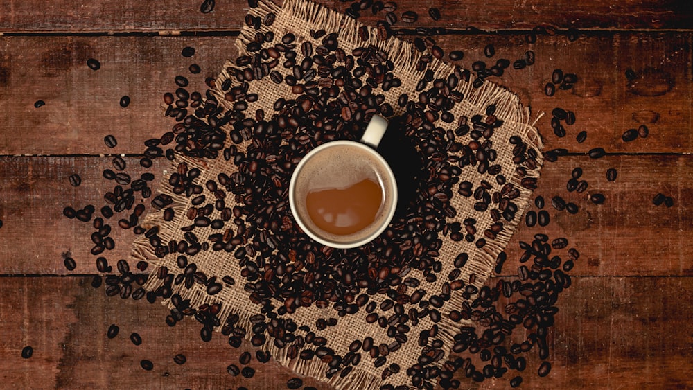 grains de café à côté d’une tasse remplie de café