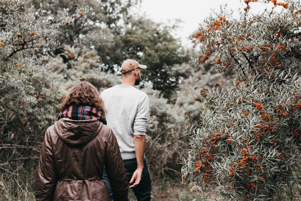 man and woman walking near trees