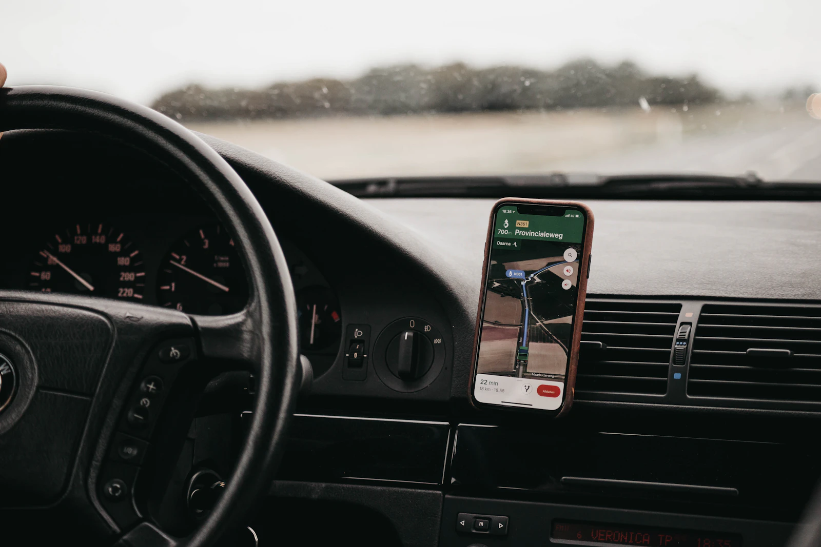 Smartfon z włączoną nawigacją zamocowany na desce rozdzielczej samochodu