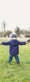 three children holding hands standing on grasses