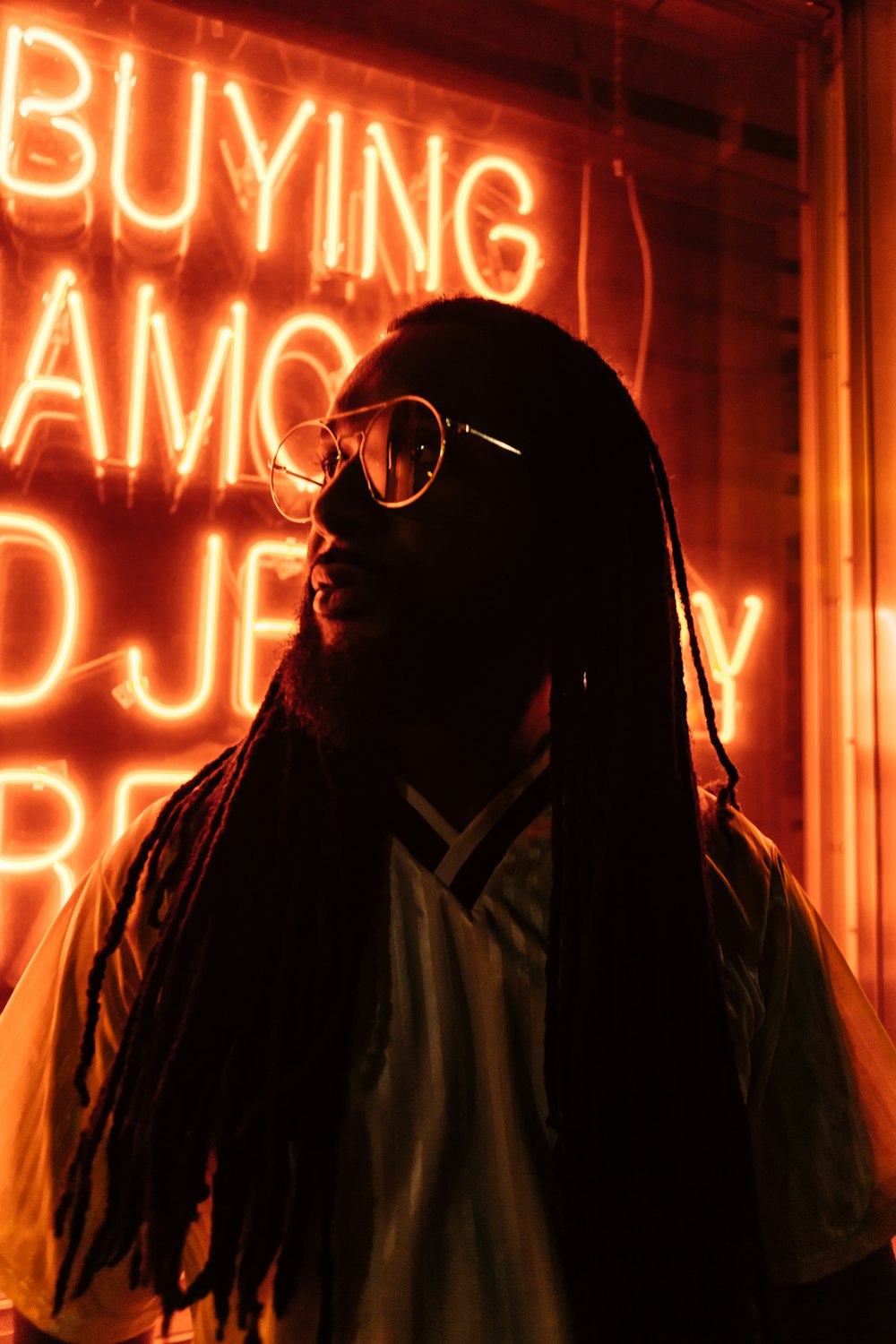 photo of man standing beside neon sign