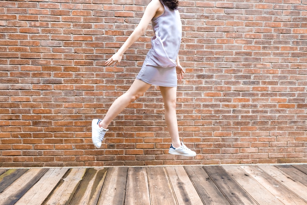 woman in white tank top and blue denim shorts standing on brown wooden floor