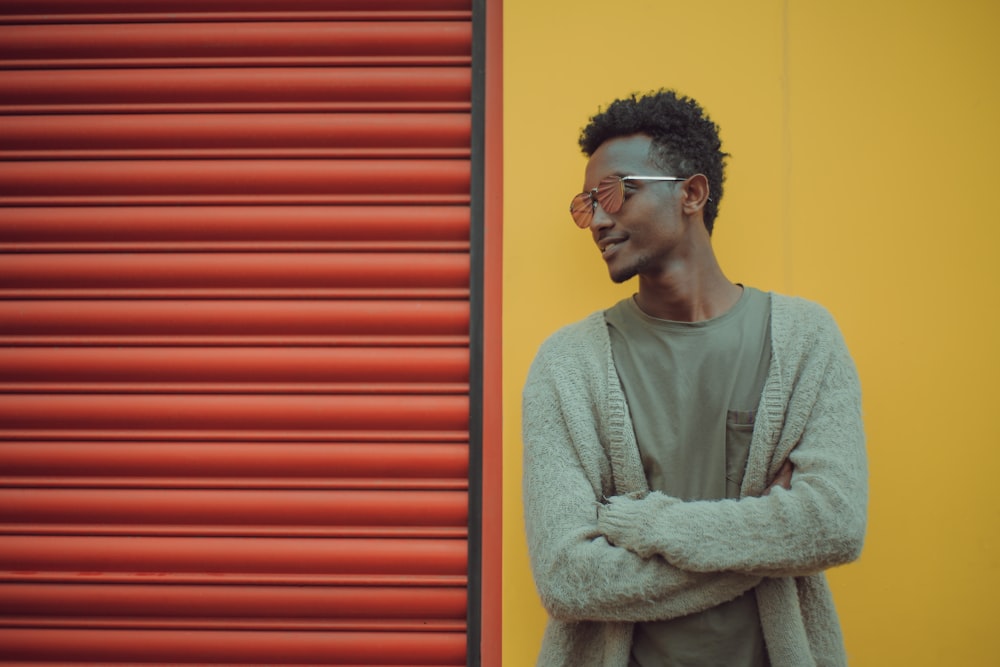 man doing cross arms while standing near red roller shutter