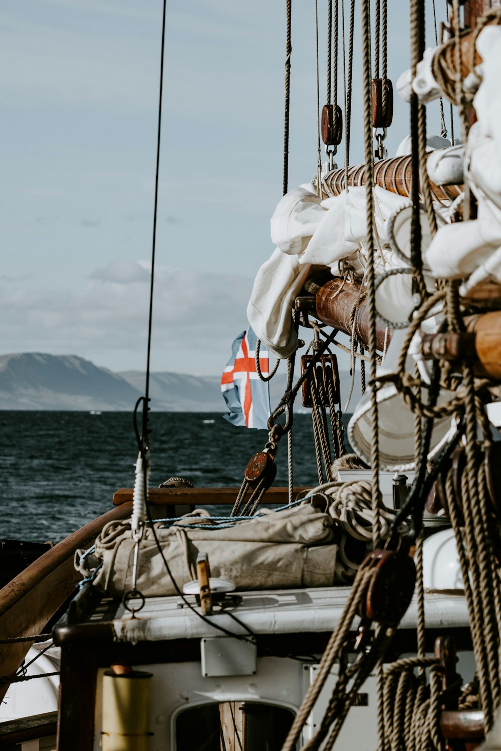 Yacht bianco e marrone sullo specchio d'acqua vicino alla catena montuosa