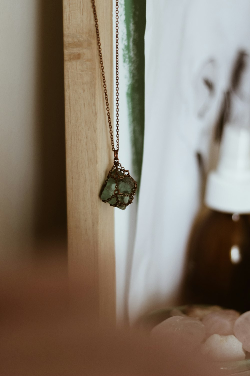 silver-colored necklace hanging on white wooden wall