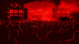 Wide-angle view of the crowd energized under the glow of red and white stage lights.