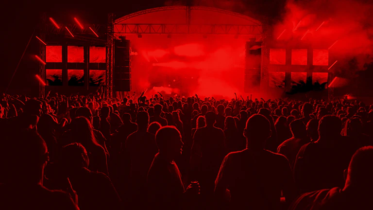 Wide-angle view of the crowd energized under the glow of red and white stage lights.