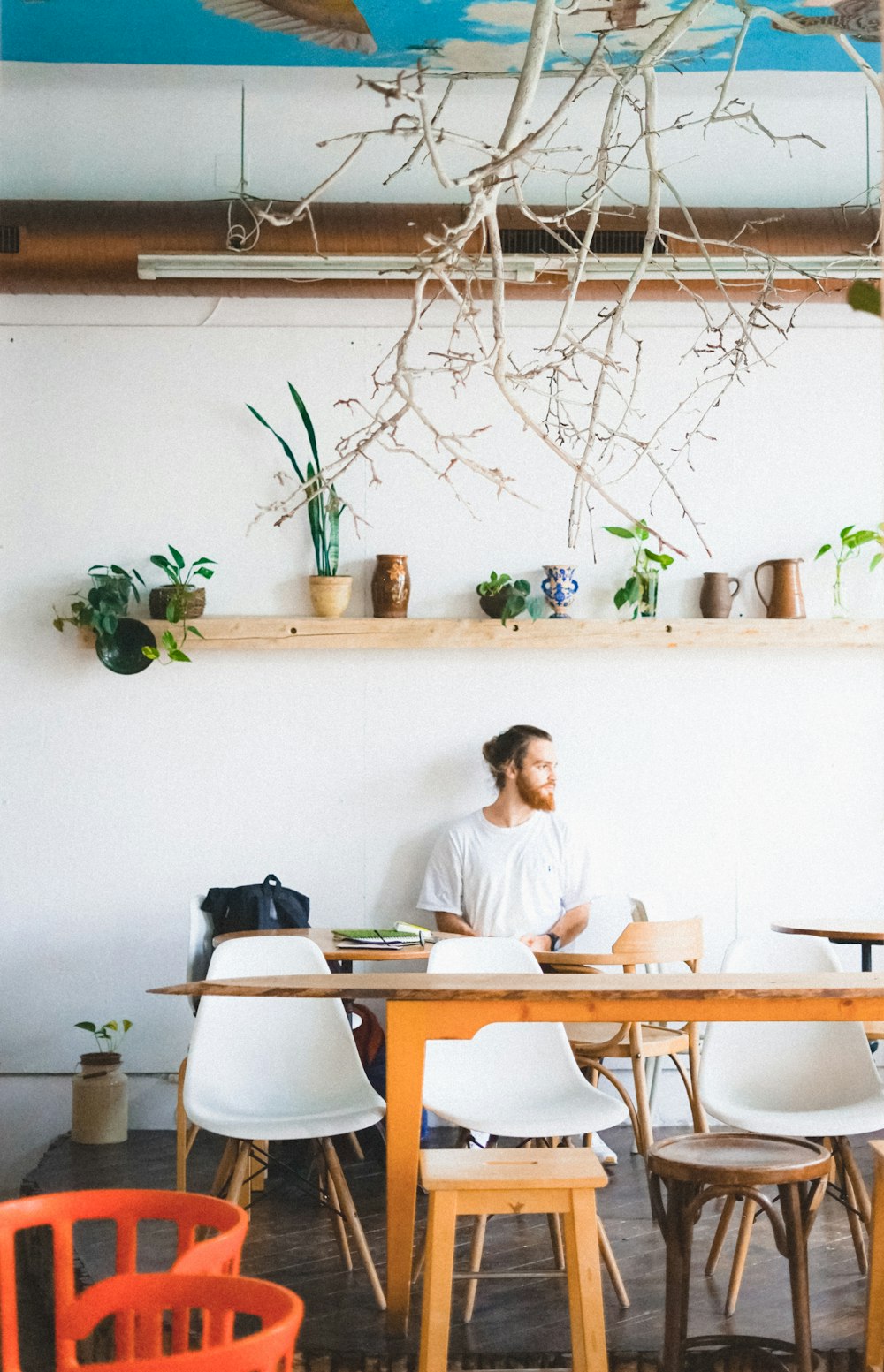 man sitting on chair under wall-mounted shelf inside room