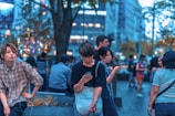 selective focus photography of man sitting on concrete chair while holding smartphone