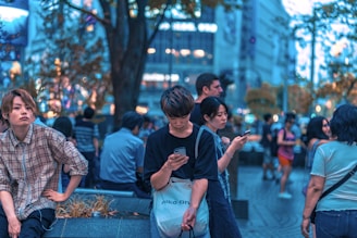 A diverse group of people engaging with mobile devices in a vibrant urban setting.