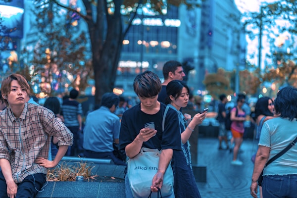 A vibrant street scene in London with people using their phones.