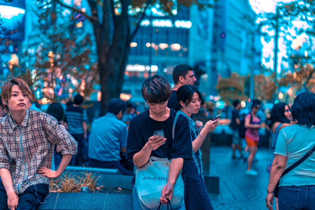 selective focus photography of man sitting on concrete chair while holding smartphone, Aeon