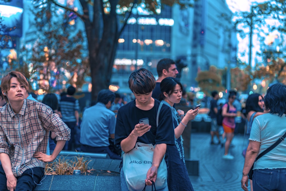 selective focus photography of man sitting on concrete chair while holding smartphone