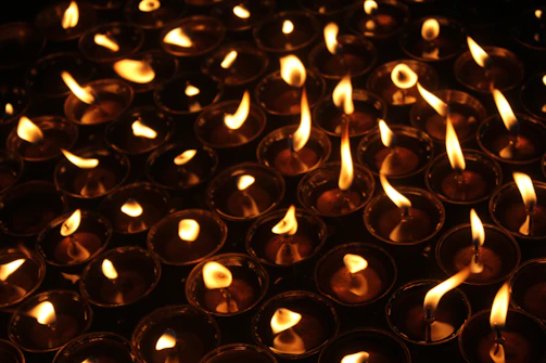 Close-up of beautifully lit lumiflamme candles glowing warmly in a dim room.