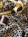 Detailed view of a sewing setup including a leopard print fabric, a yellow measuring tape, a spool of brown thread, and a pair of metal scissors.