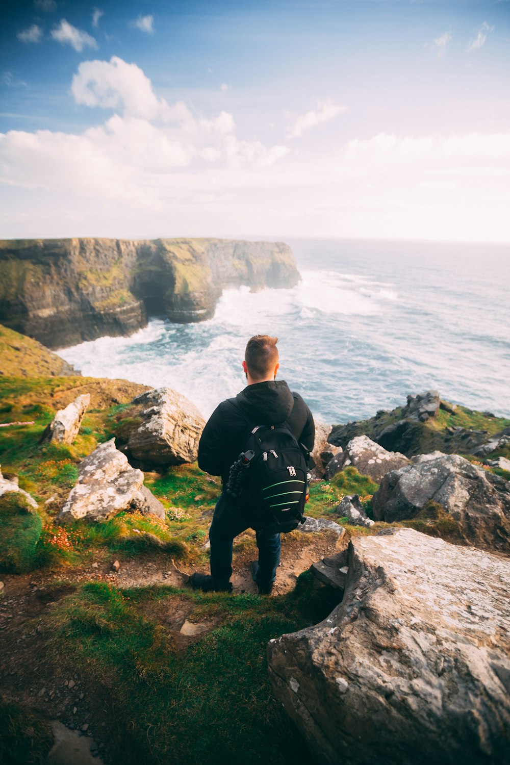 man standing on green and brown cliff