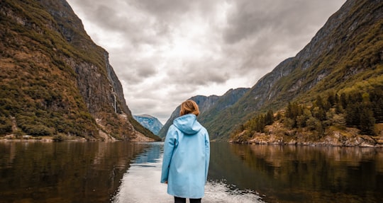 person wearing blue hooded jacket facing mountain in Gudvangen Norway