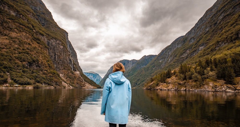 person wearing blue hooded jacket facing mountain