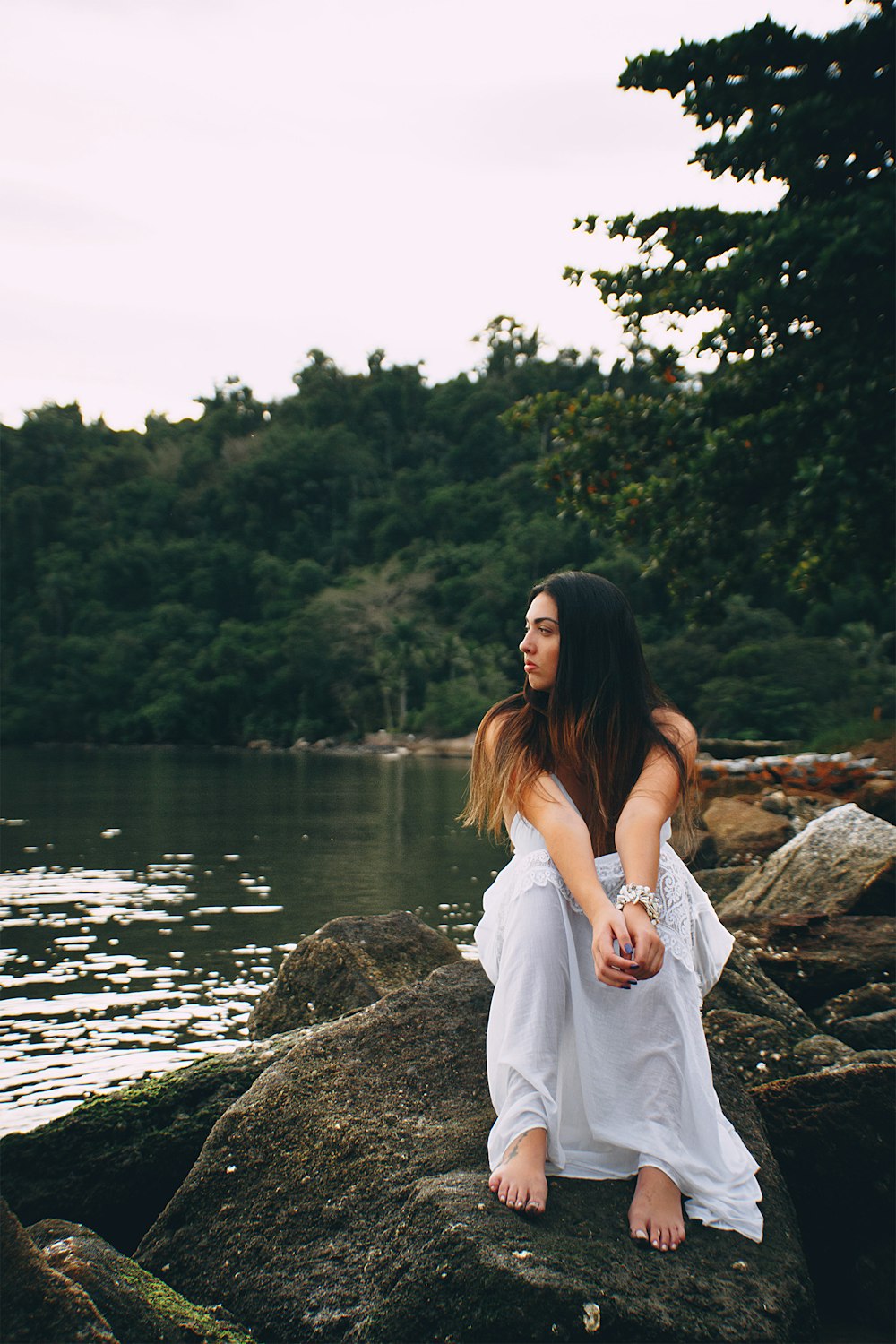 woman sitting on rock beside water